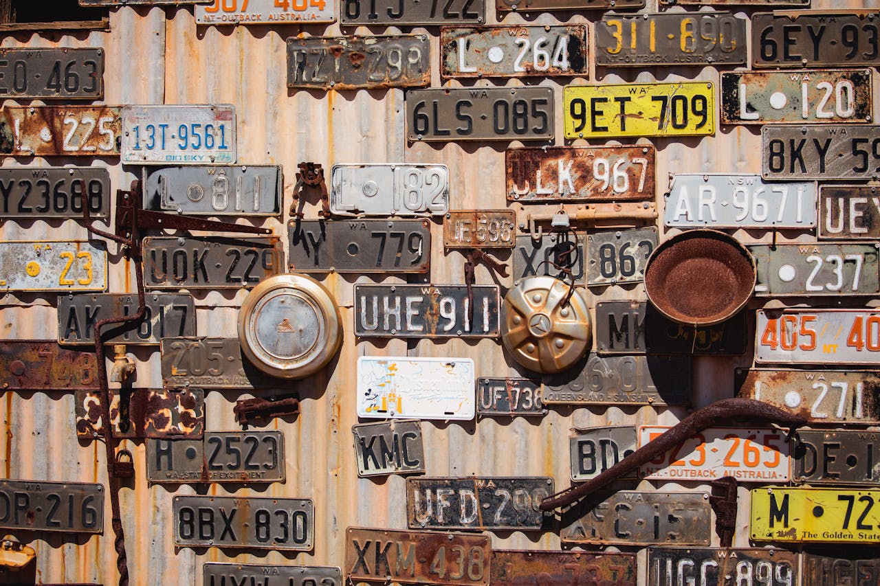 services-02 Collection of vintage license plates displayed on a corrugated metal wall in Leonora, Australia.